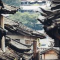 geography 人文地理研究者站在城市高处的落地窗前记录街区布局，窗外密集楼宇与道路延伸至远处，黄昏冷调光线